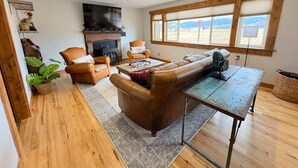 Una sala de estar acogedora con chimenea, sofás de cuero, una mesa de centro y un ventanal con vistas.