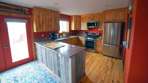 Una cocina con armarios de madera, un refrigerador de acero inoxidable, un microondas y una estufa.