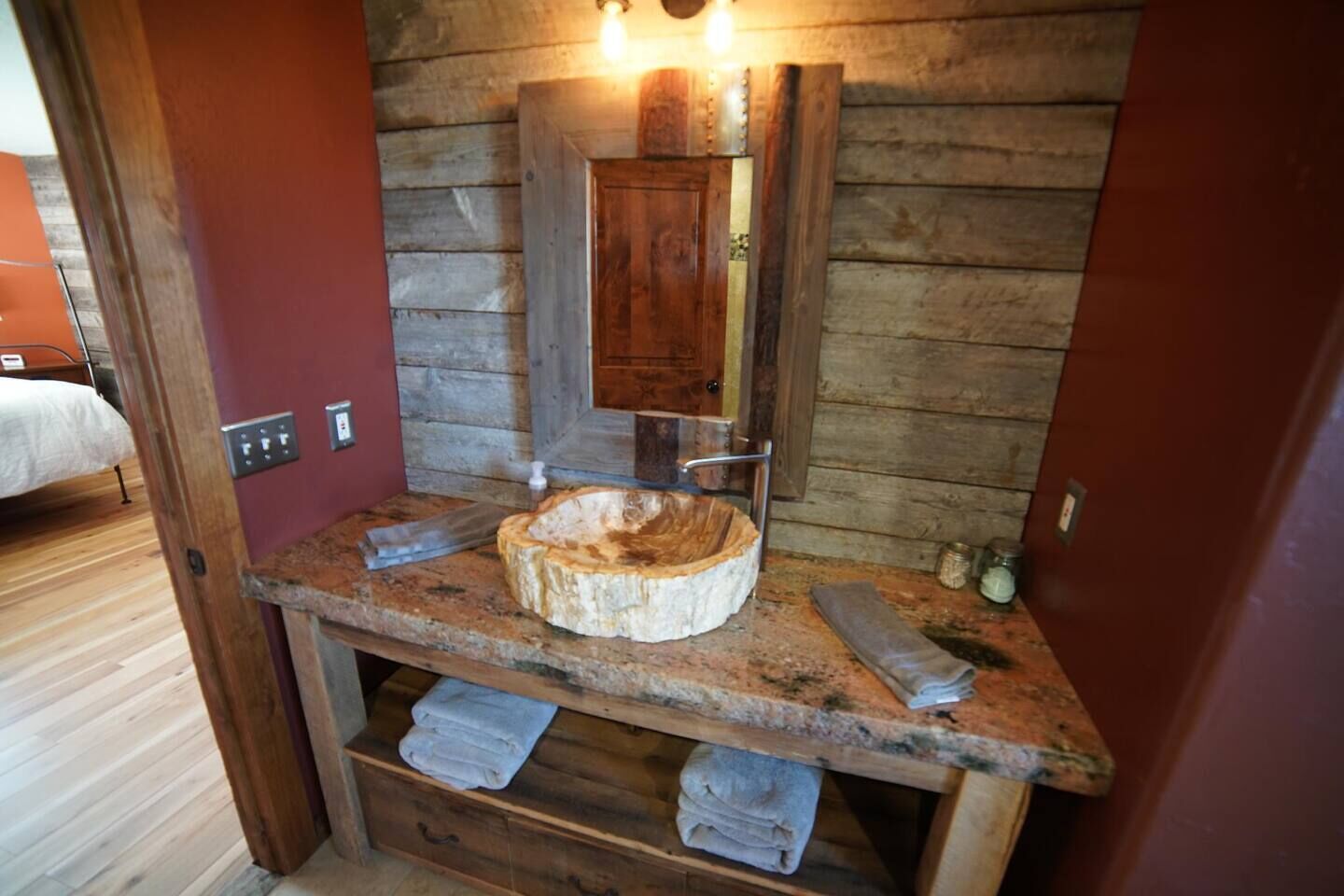 Une salle de bain rustique avec un meuble-lavabo en bois, un lavabo rond et un miroir au-dessus.