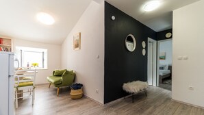 En modern lägenhet med kök, matplats och vardagsrum med en grön soffa och ett litet runt bord.