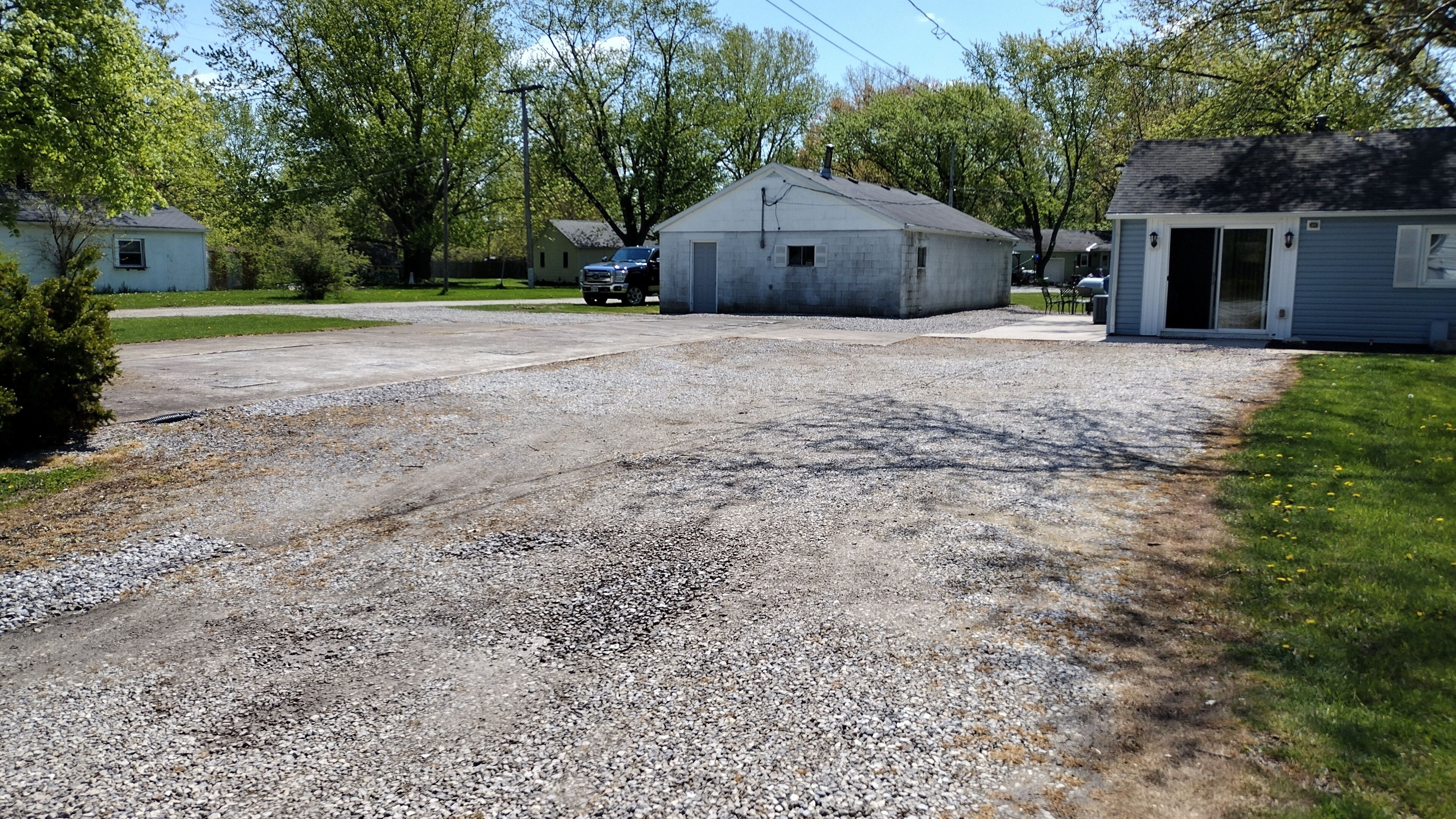 A gravel driveway leading to a small, single-story building with a garage.