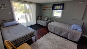 Una habitación con dos camas individuales, un sofá, una ventana con cortinas y una tabla de remo fijada a la pared.