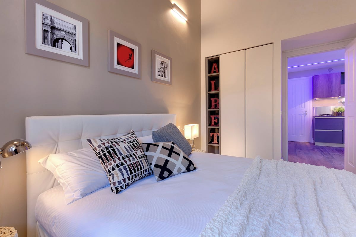 Ein ordentlich eingerichtetes Schlafzimmer mit einem großen Bett, Nachttischlampen und einem Kleiderschrank.