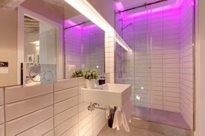 Ein modernes Badezimmer mit Waschbecken, Spiegel und Duschkabine aus Glas.