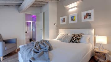 Un dormitorio con una cama grande, una mesita de noche con lámpara y una silla.