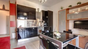 A modern kitchen with a dining area, a TV, and a red sofa. - Mamo Florence - Binario 9 Apartment (Florence)
