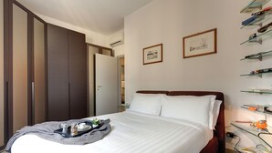 A neatly made bed with a tray of breakfast items, a bedside table with a lamp, and a wall with framed pictures. - Mamo Florence - Binario 9 Apartment (Florence)