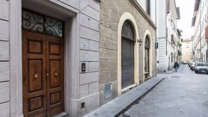Eine enge Straße mit einem Gebäude, das eine große Holztür und Bogenfenster besitzt.