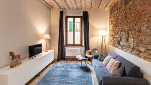 Ein gemütliches Wohnzimmer mit Fernseher, Sofa und einer Steinwand.