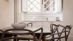A dining area with a table and chairs, a window with a diamond-patterned design, and a white sink. - Mamo Florence - Costa San Giorgio Apartment (Florence)