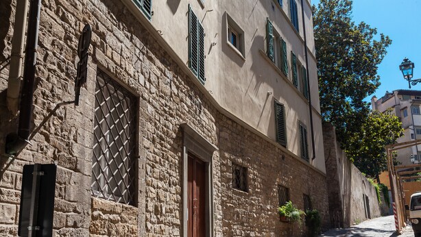 A narrow cobblestone street with stone buildings, a wooden door, and a parked vehicle. - Mamo Florence - Costa San Giorgio Apartment (Florence)