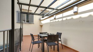 A terrace with a table and chairs, a window with shutters, and a metal railing. - Mamo Florence - Cupolone Apartment (Florence)
