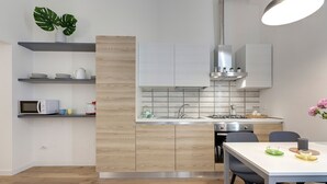 Een moderne keuken met houten kastjes, een wit aanrecht en een eethoek met een tafel en stoelen.