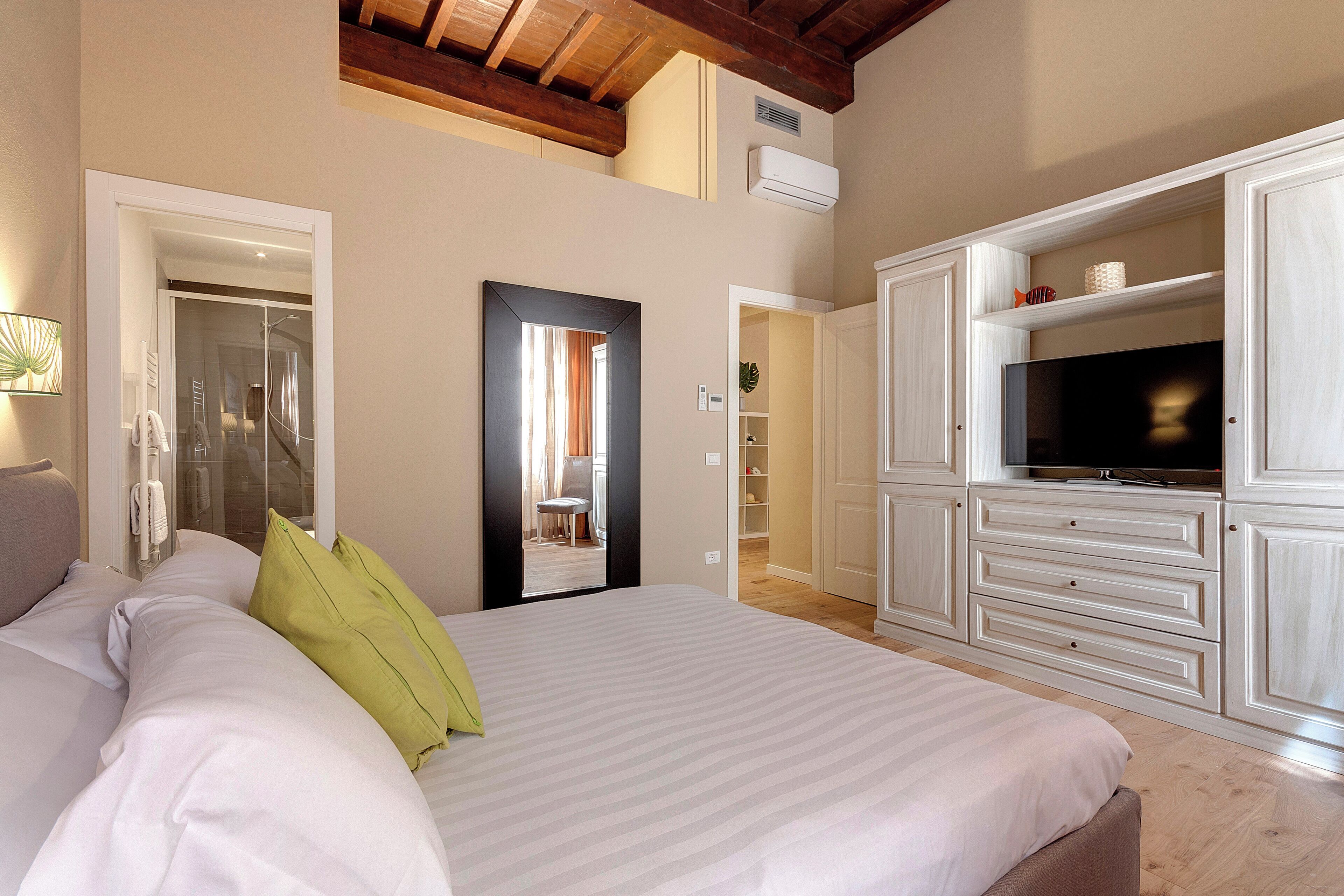 A bedroom with a large bed, a TV, and a wardrobe.