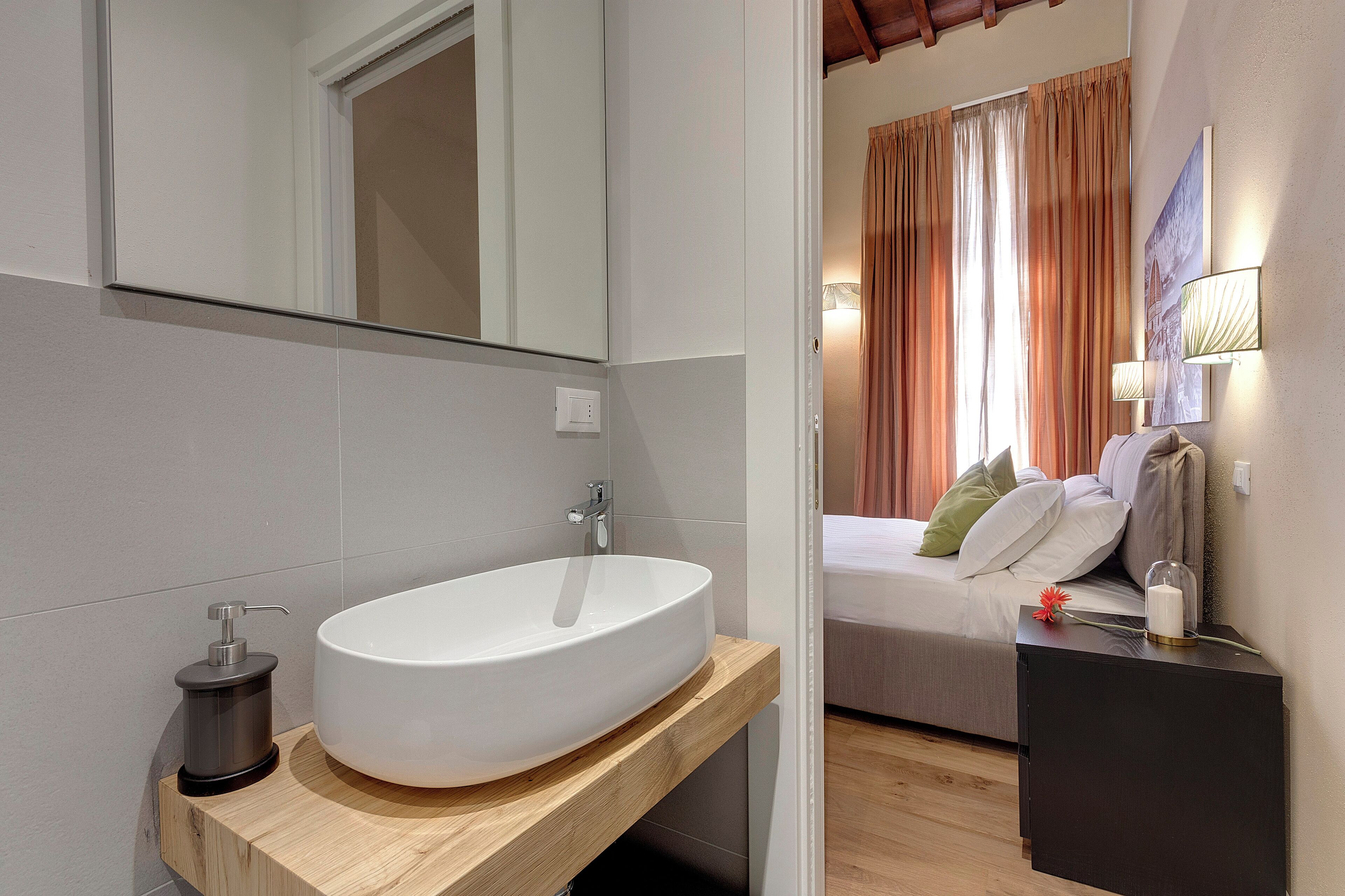 Une salle de bain moderne avec un grand lavabo blanc, un miroir et un meuble-lavabo en bois.