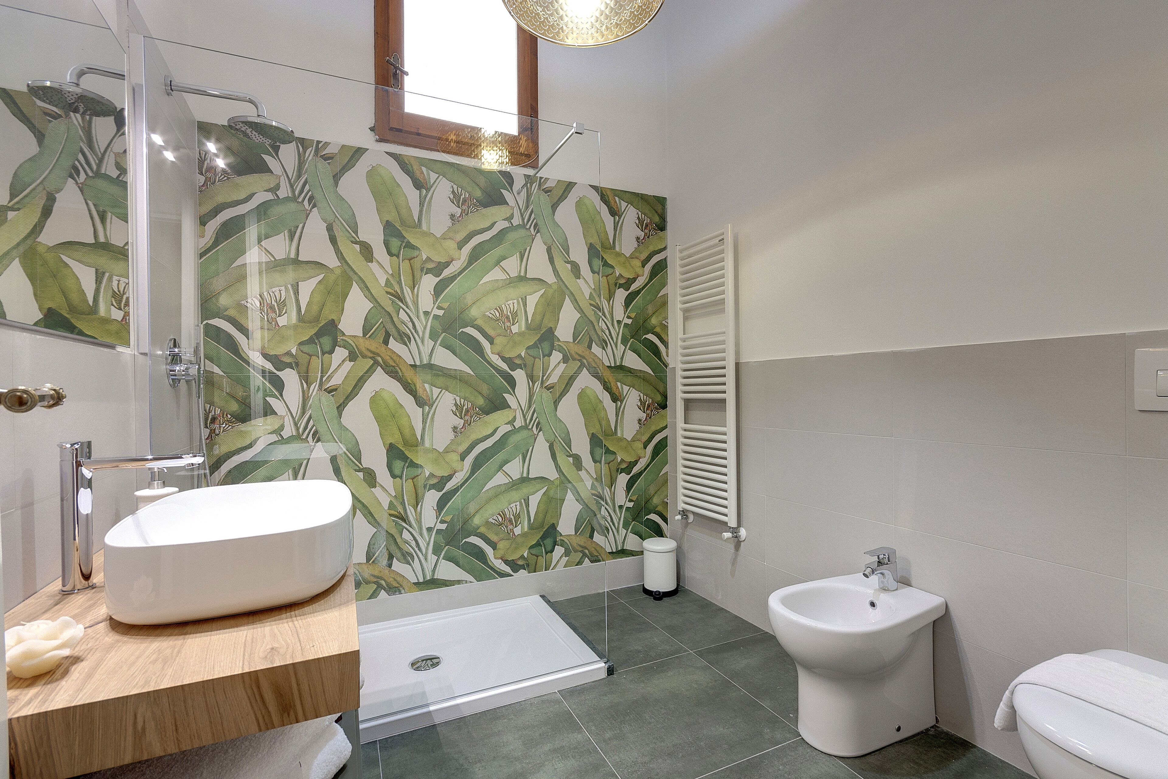 A bathroom with a large mirror, a freestanding bathtub, a bidet, and a toilet.