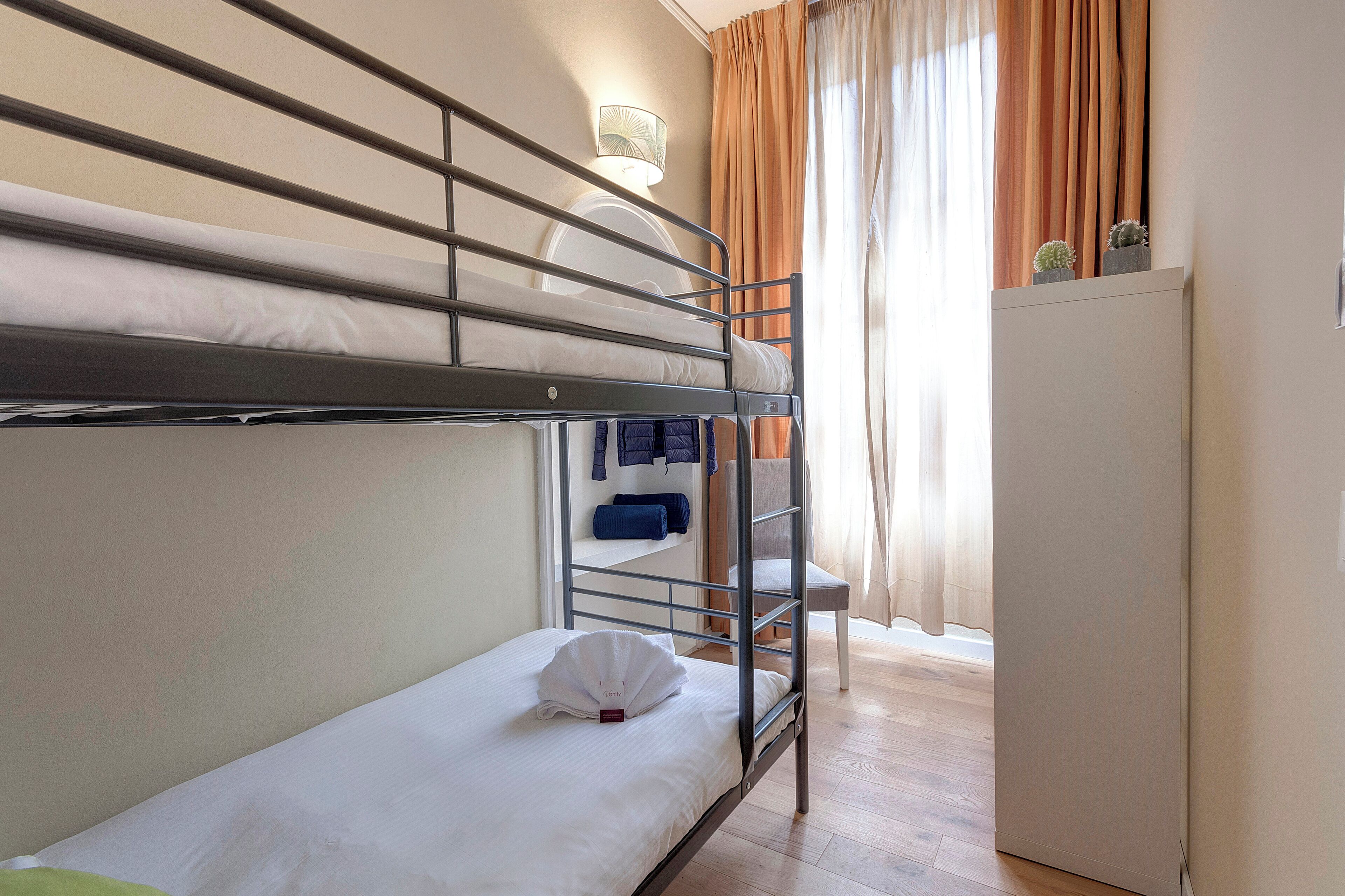 A bunk bed room with a desk and a lamp.