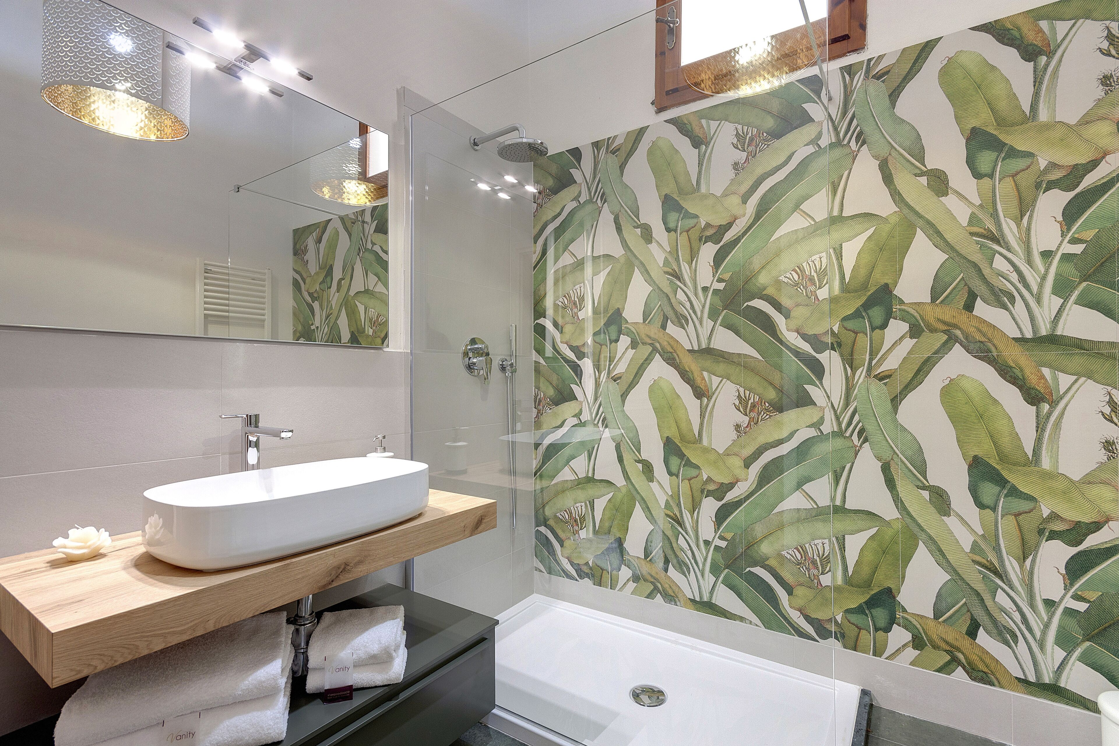 A modern bathroom with a white sink, wooden vanity, and a shower area with a glass door.