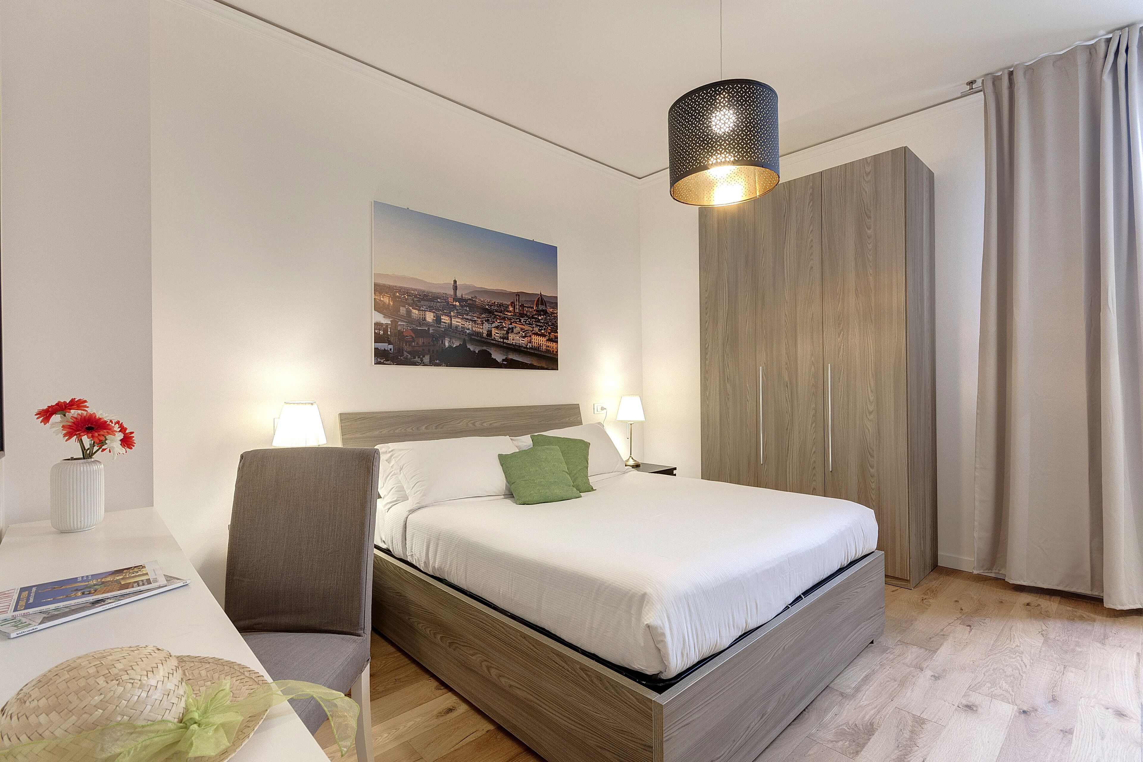Une chambre d’hôtel moderne avec un grand lit, une tête de lit en bois et un tableau représentant un paysage urbain accroché au mur.