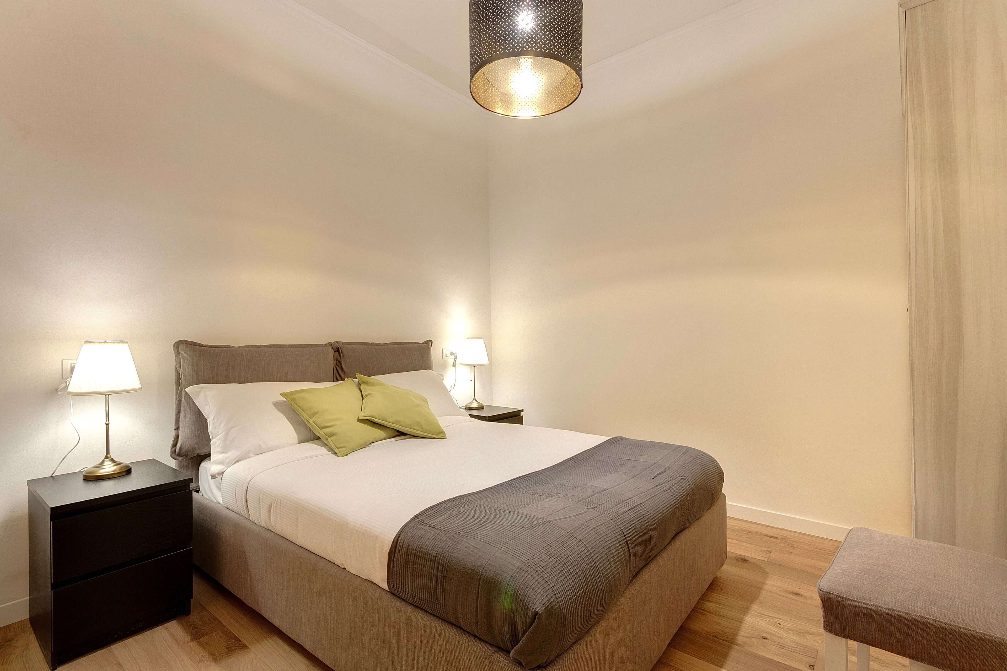 Ein ordentlich eingerichtetes Schlafzimmer mit Bett, Nachttischen, Lampen und einer Pendelleuchte.