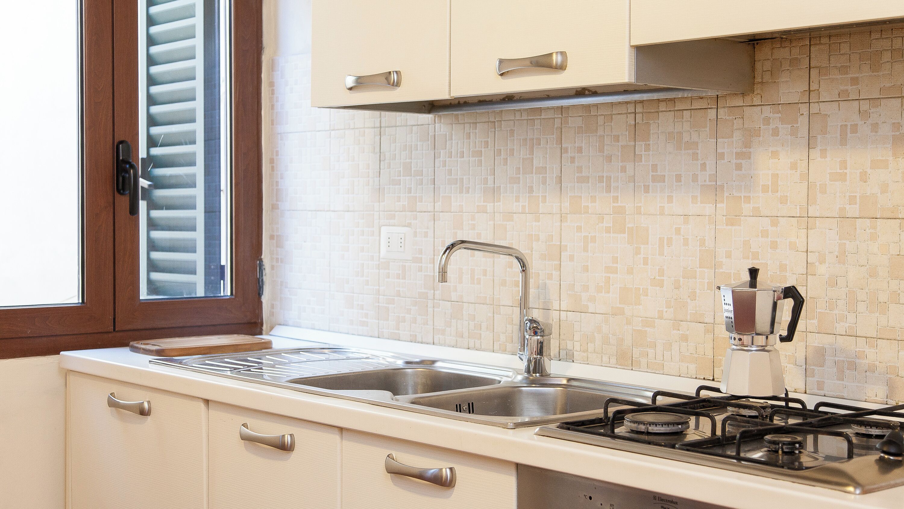 A kitchen with a double sink, stainless steel faucet, and a gas stove.