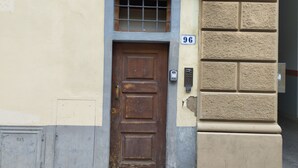 A brown wooden door with a small window above it, a doorbell, and a mailbox on the wall. - Mamo Florence - Palazzuolo Tower (Florence)