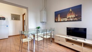 A modern kitchen with a microwave, a refrigerator, and a dining area with a glass table and chairs. - Mamo Florence - Palazzuolo Tower (Florence)