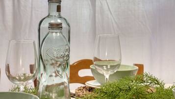 Une table mise avec une bouteille en verre transparent, deux verres à vin et un bol vert.