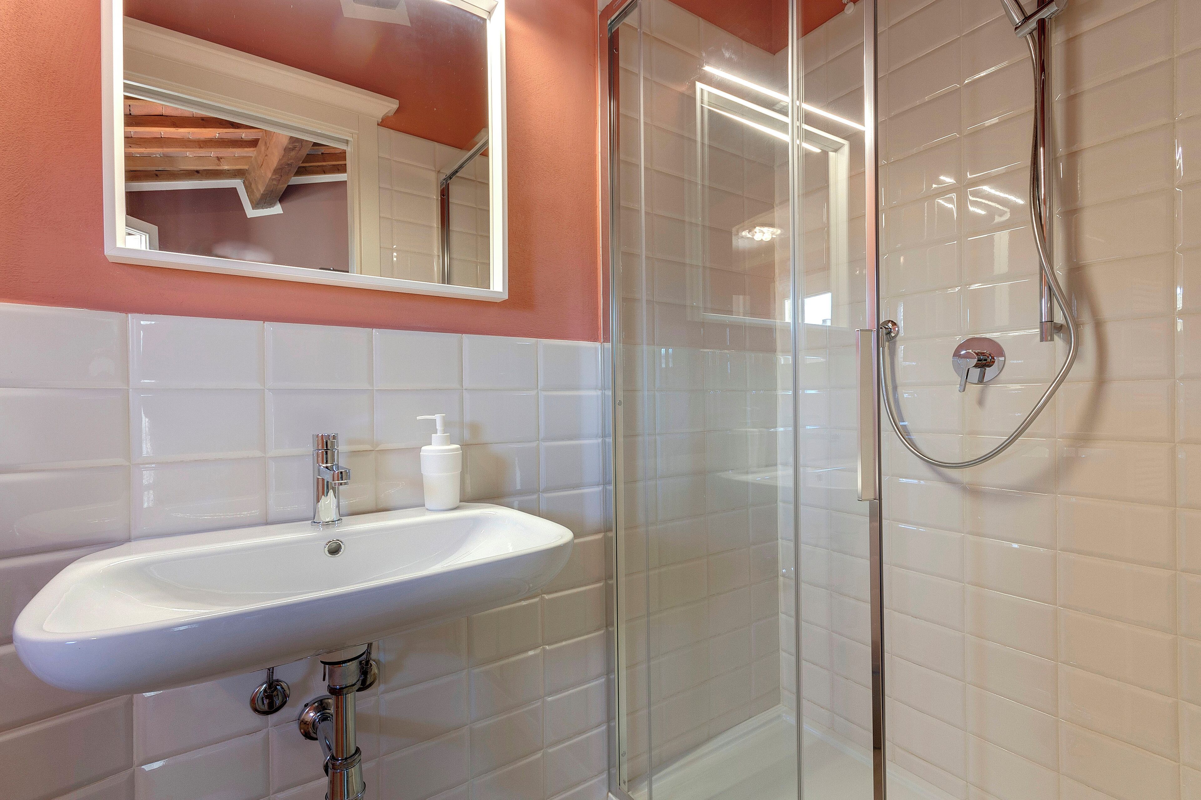A bathroom with a white sink, a glass-enclosed shower, and a mirror above the sink.