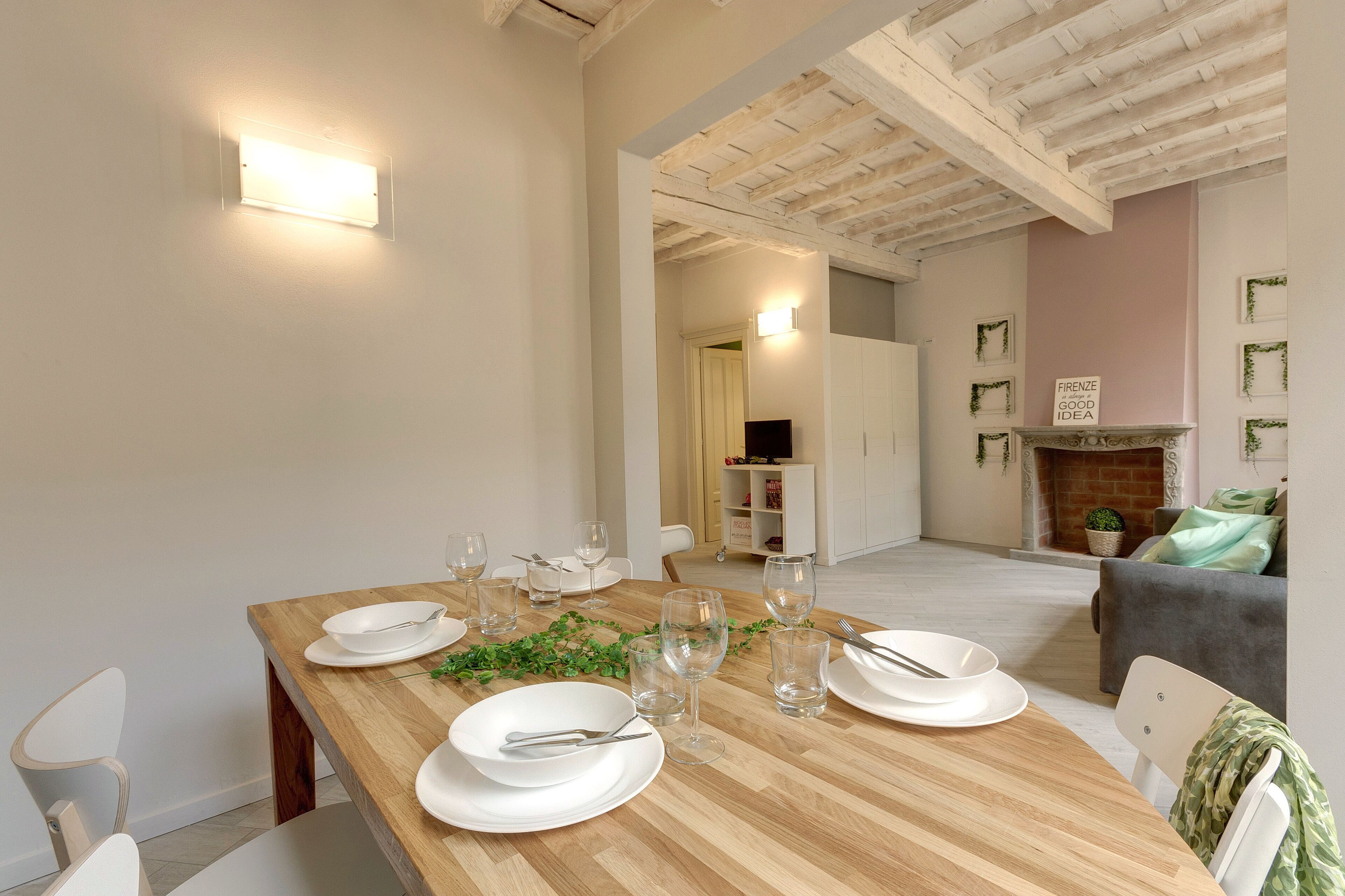 A dining area with a wooden table set for four, white plates, and clear glassware.