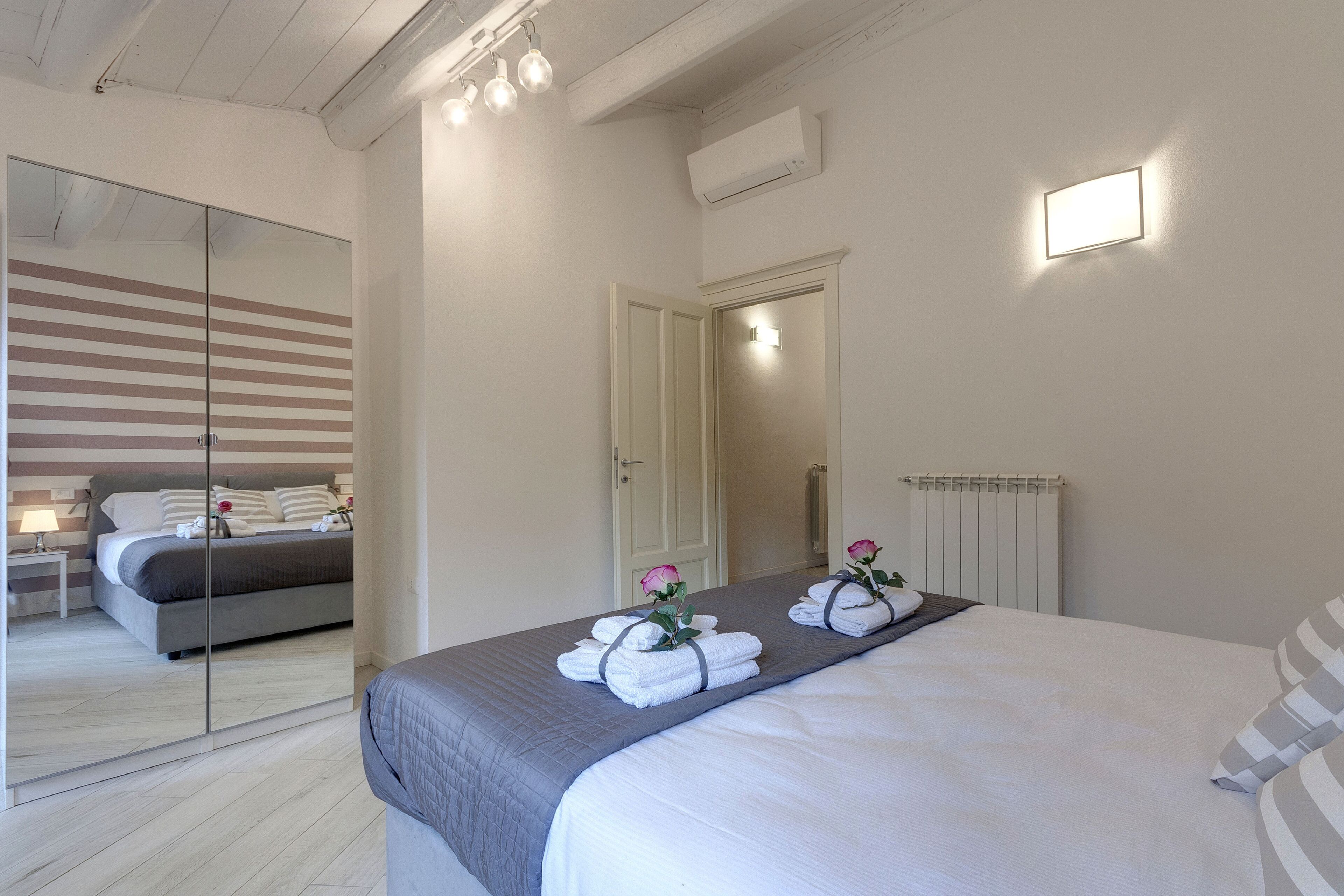A hotel room with a large bed, a bedside table, a mirror, and a radiator.