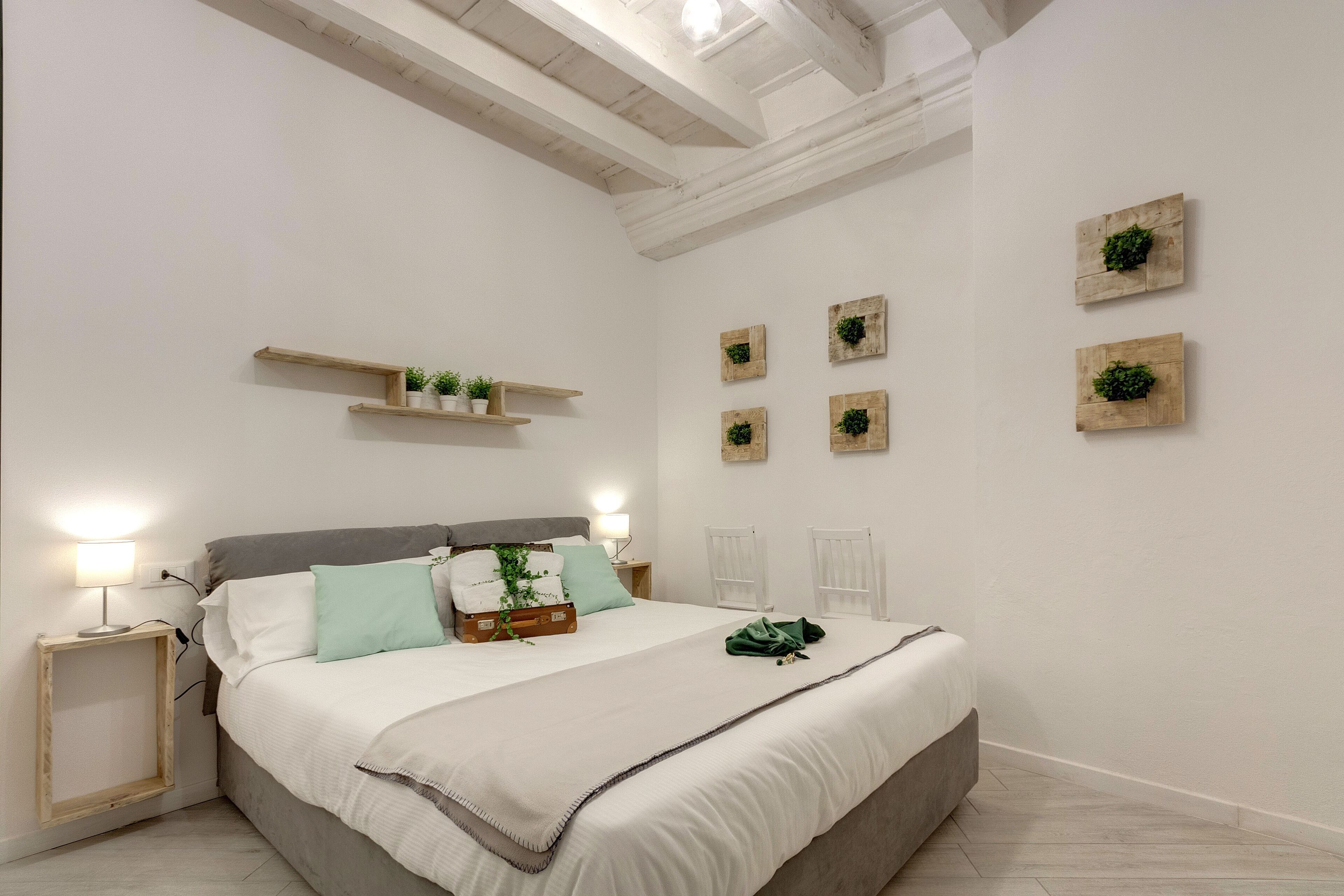 Een slaapkamer met een bed, nachtkastjes, wandplanken en decoratieve muurkunst.