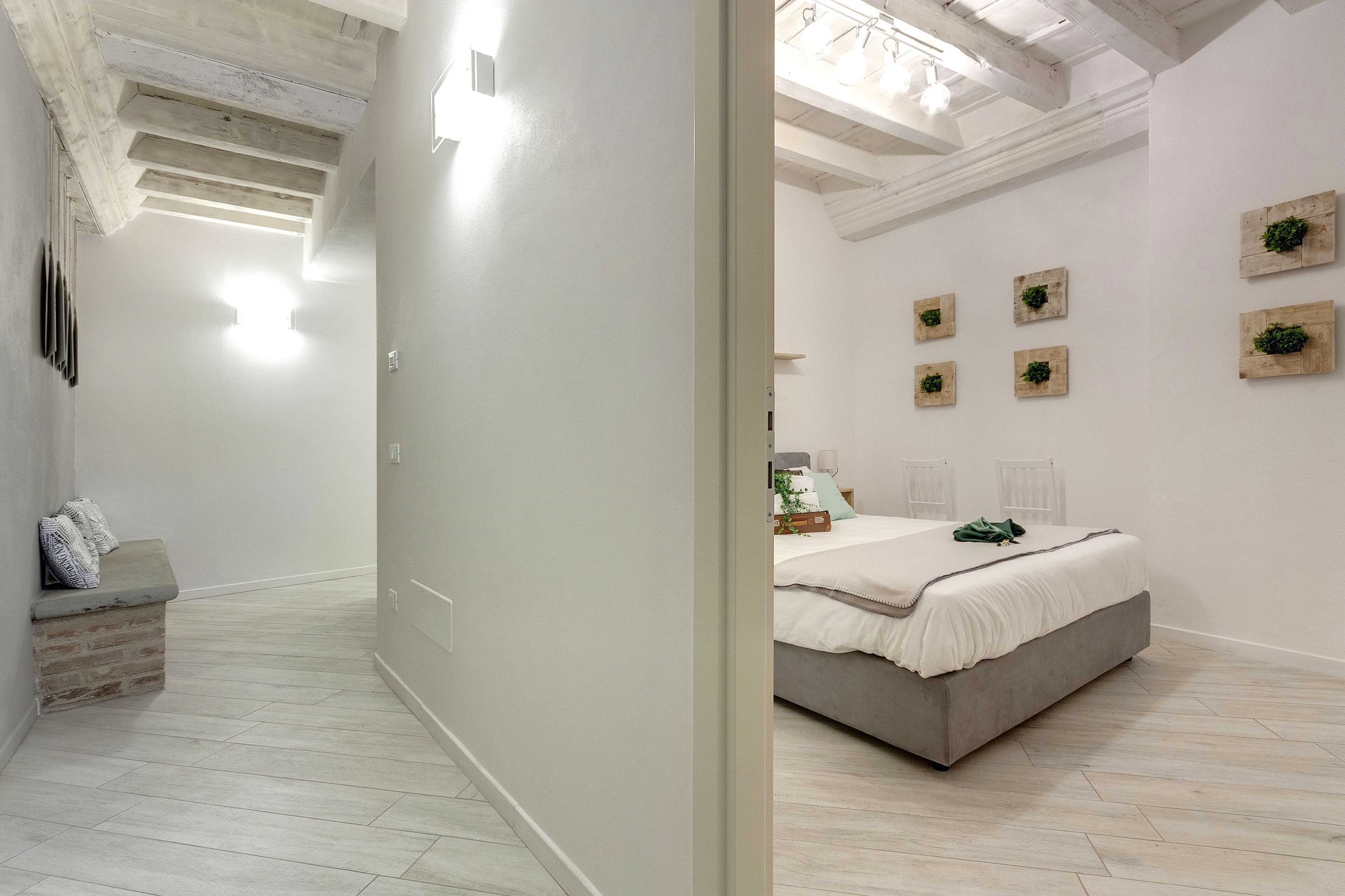 Un dormitorio con una cama, un banco y una estantería fijada a la pared.