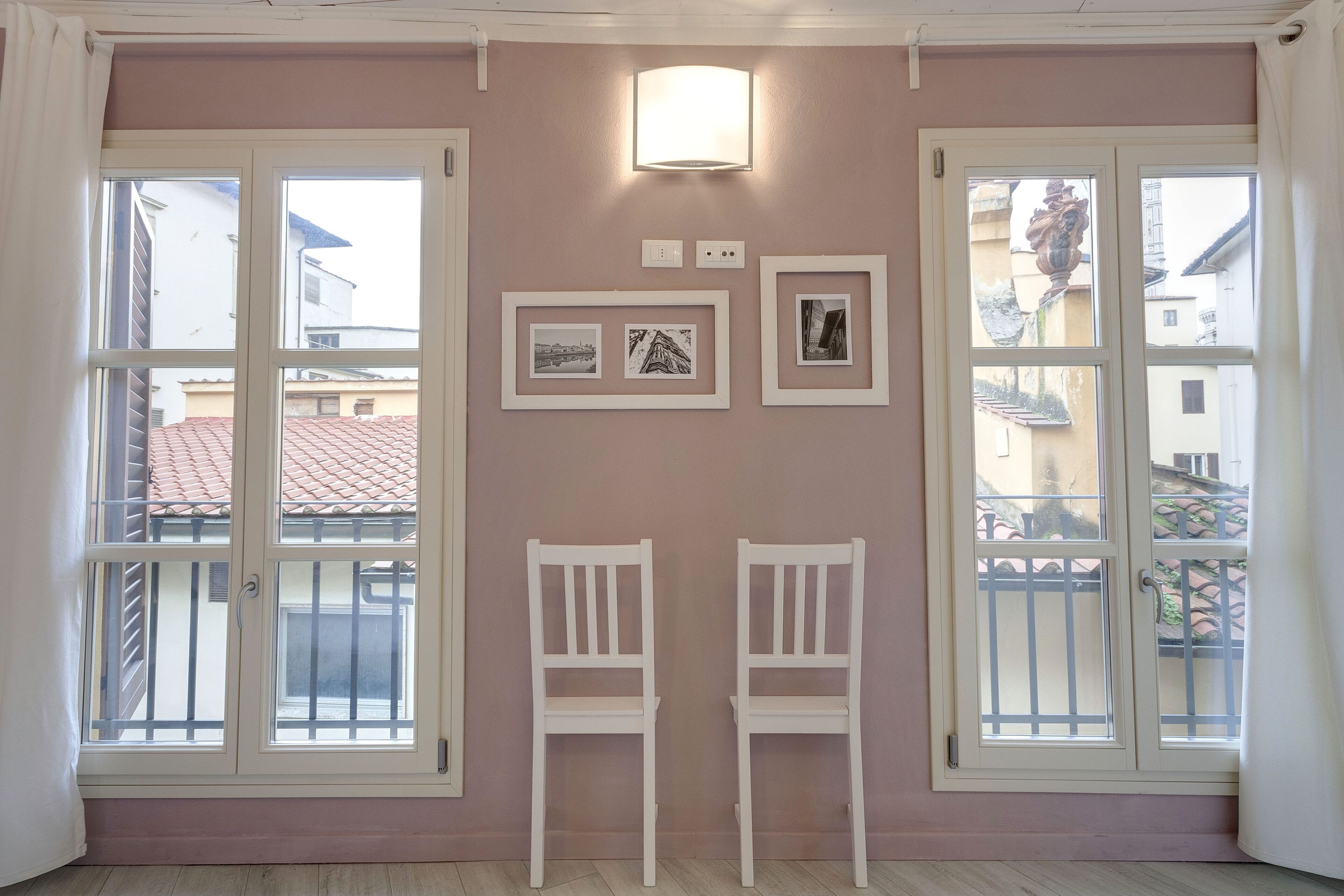 A room with two white chairs, a wall-mounted light, and framed pictures.