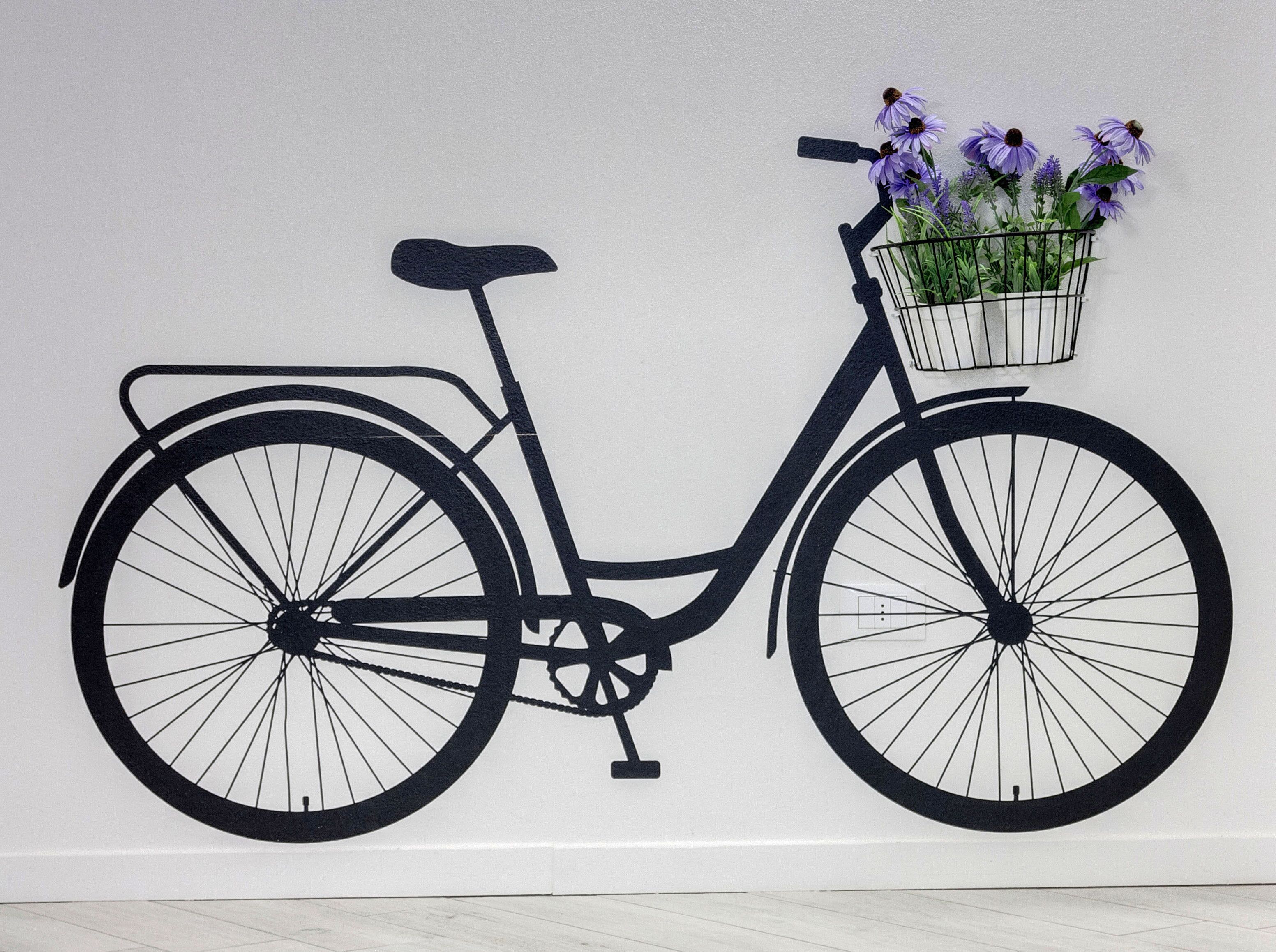 A wall-mounted black bicycle with a basket containing purple flowers.