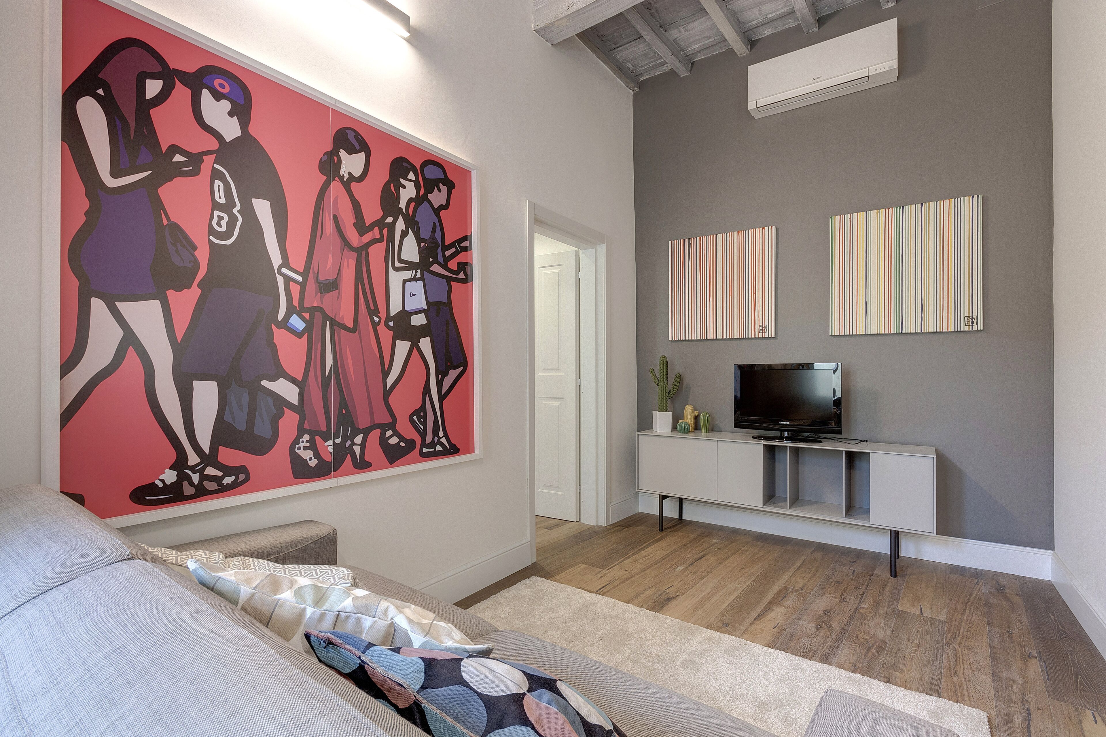 Un salon moderne agrémenté d’un grand tableau abstrait, d’un téléviseur à écran plat et d’une console au design minimaliste.