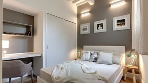 A bedroom with a bed, bedside tables, a desk, and a chair. - Mamo Florence - Il Moro Apartment (Florence)