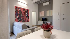A modern living room with a grey sofa, a white coffee table, and a red abstract painting. - Mamo Florence - Il Moro Apartment (Florence)