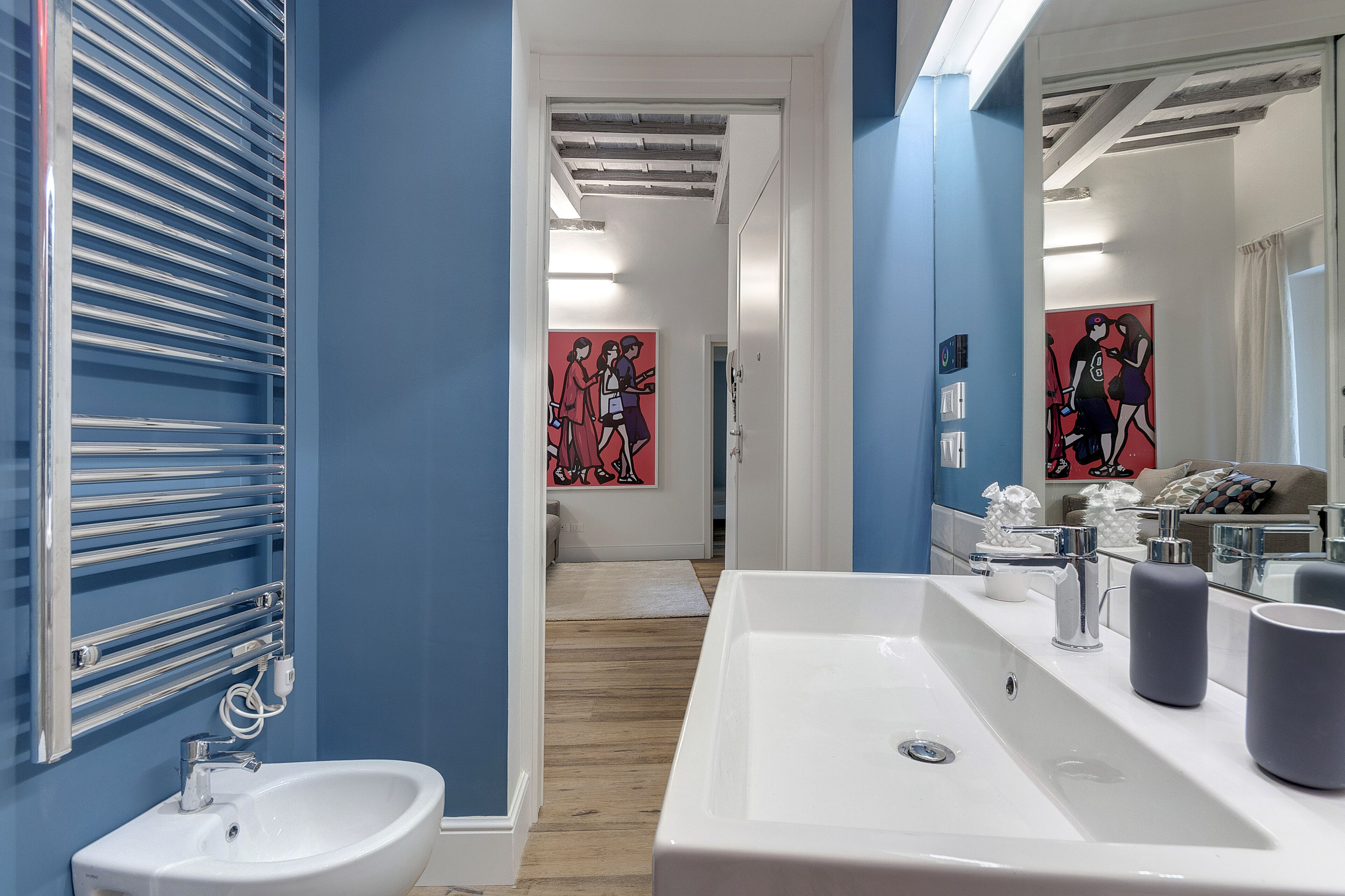 Une salle de bain moderne avec un lavabo blanc, un miroir et un porte-serviettes.