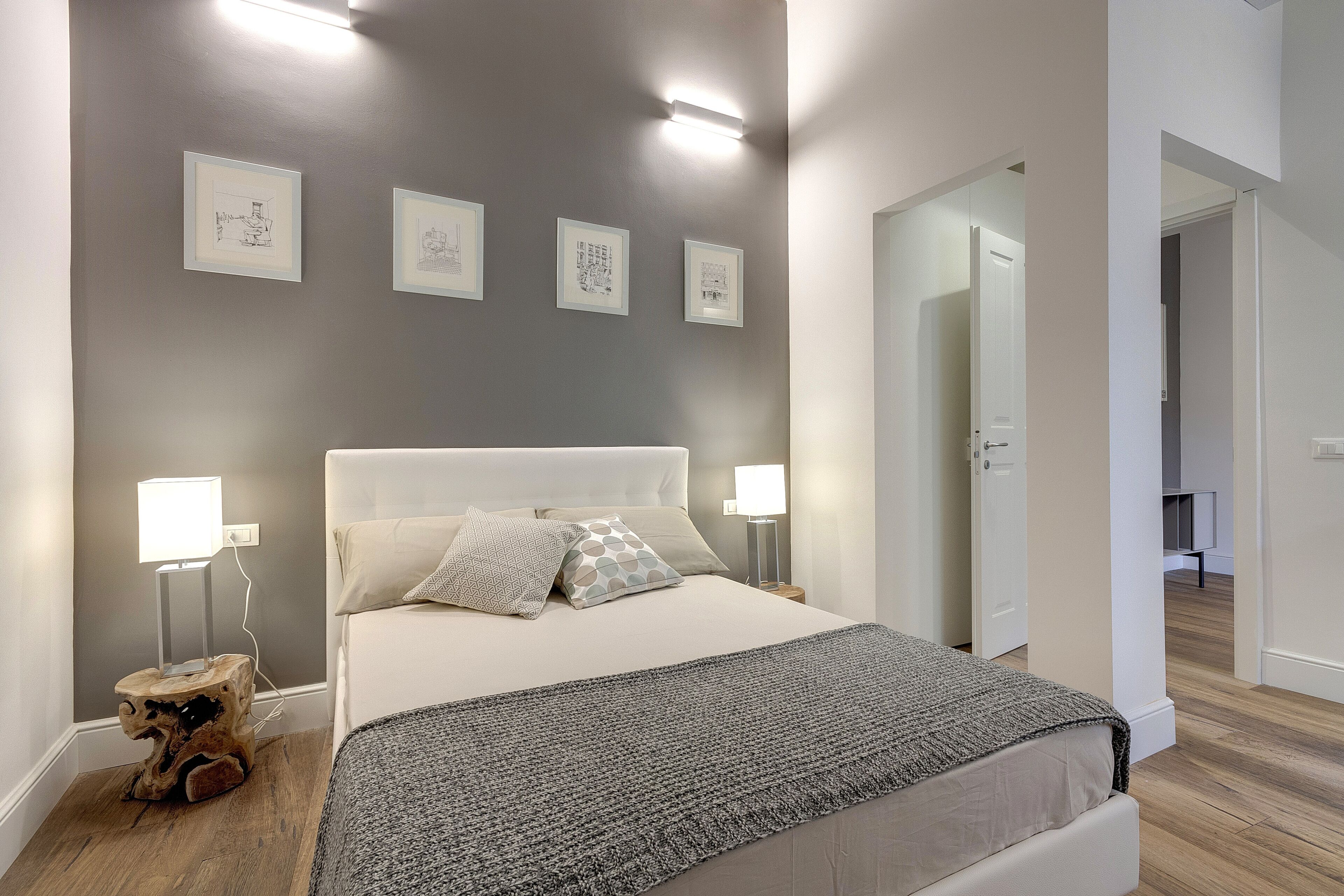 Ein modernes Schlafzimmer mit einem großen Bett, Nachttischlampen und gerahmten Kunstwerken an der Wand.