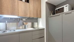 A modern kitchen with grey cabinets, a stainless steel sink, and a microwave on the countertop. - Mamo Florence - Il Moro Apartment (Florence)