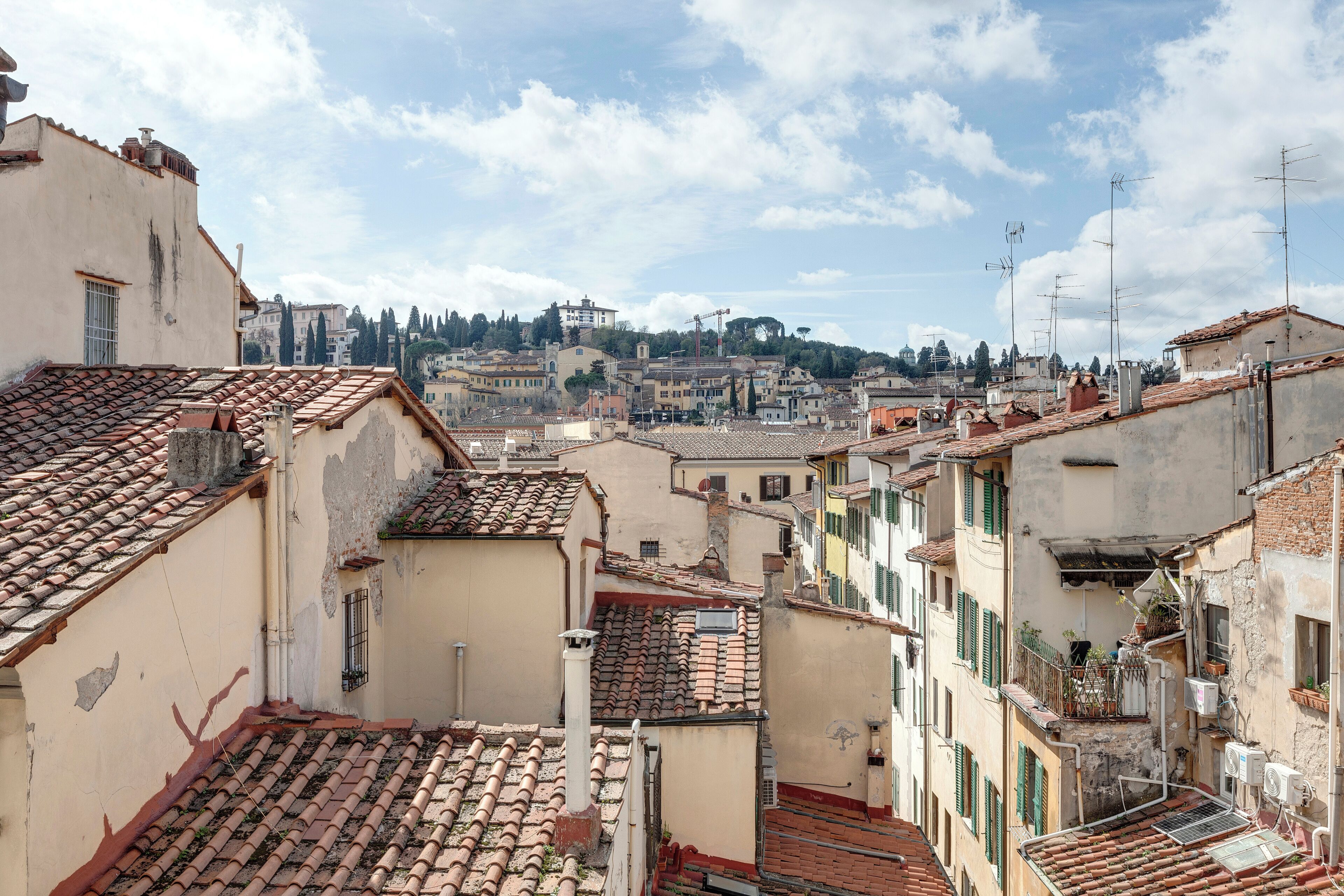 A narrow street with terracotta-tiled roofs and buildings with balconies.