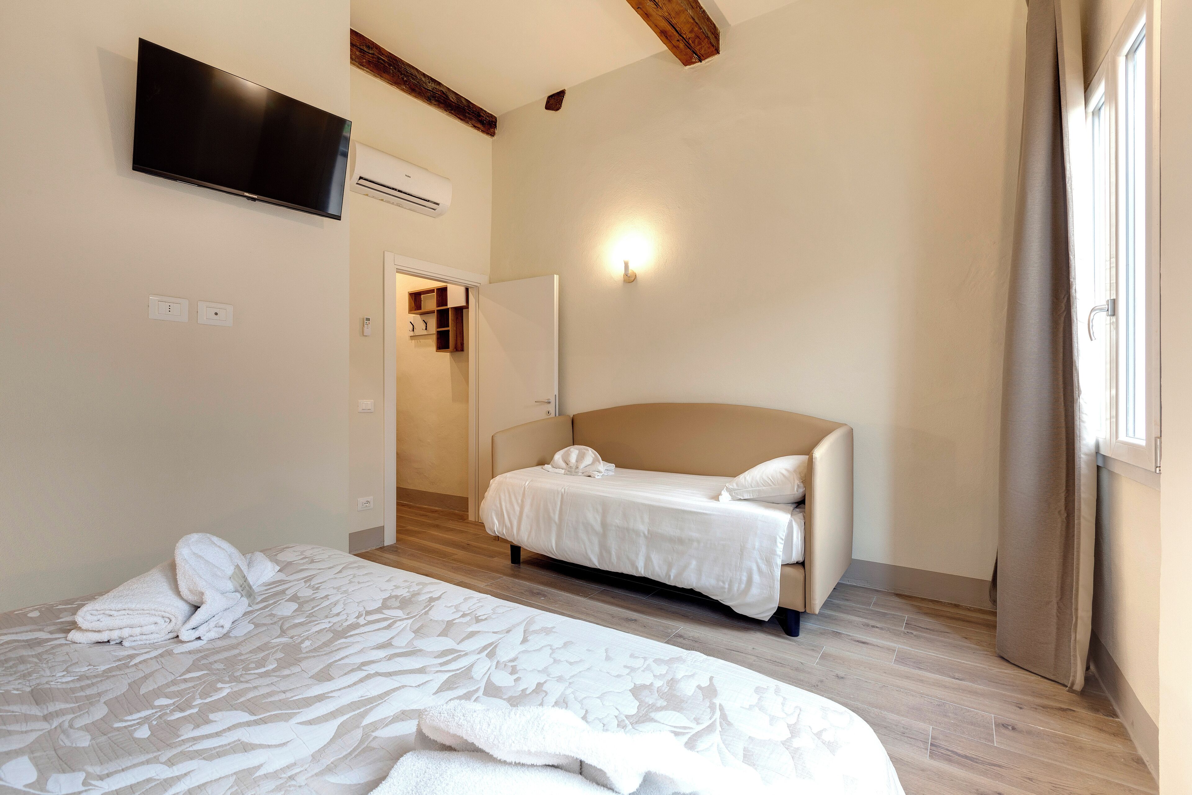 A bedroom with a bed, a TV mounted on the wall, and a door leading to a bathroom.