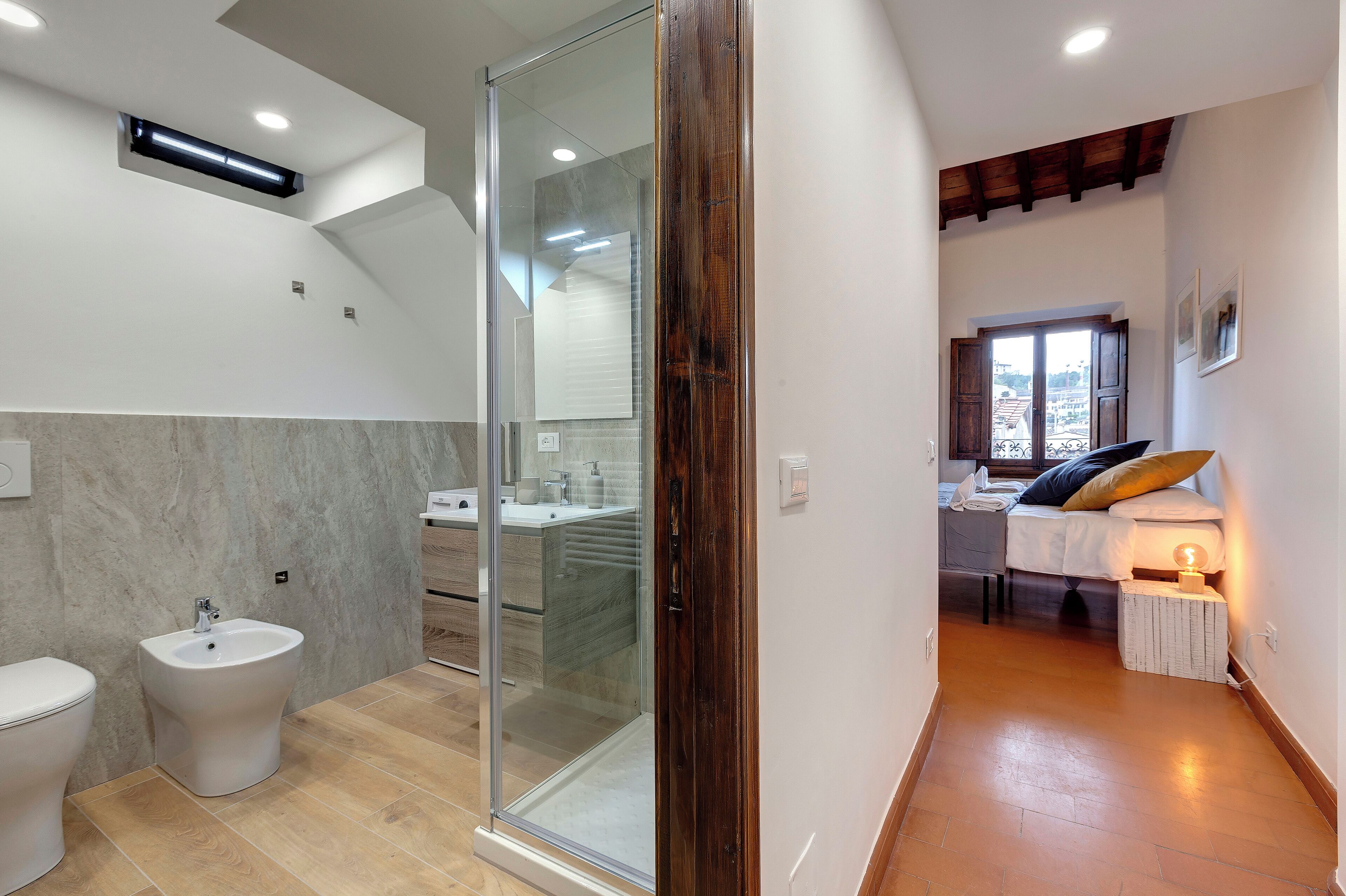 A modern bathroom with a bidet, a glass shower enclosure, and a white toilet.