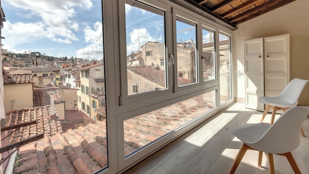 A room with large windows, white chairs, and a view of a cityscape. - Mamo Florence – Neri22 Apartments (Florence)