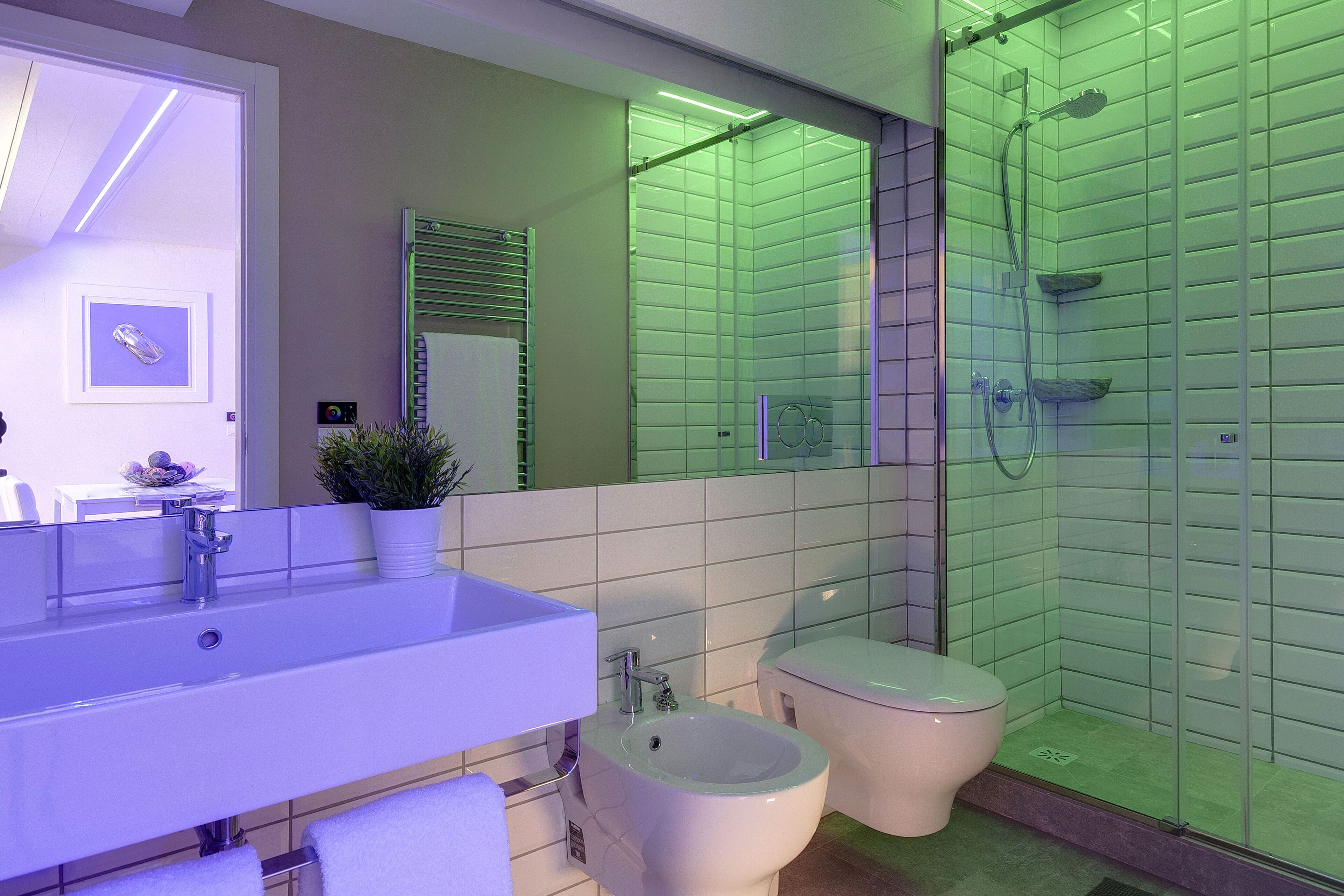 Een moderne badkamer met een groot wastafel, toilet, bidet en een douchecabine met glazen wanden.