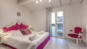 A bedroom with a bed, a chair, a nightstand, and a window with a view. - Mamo Florence – Victor Apartment (Florence)
