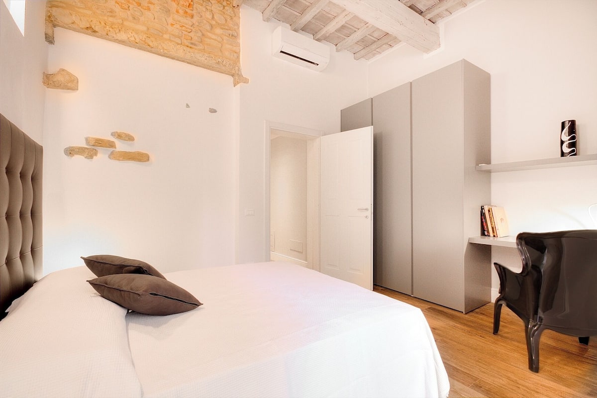 A bedroom with a bed, a chair, and a wardrobe.