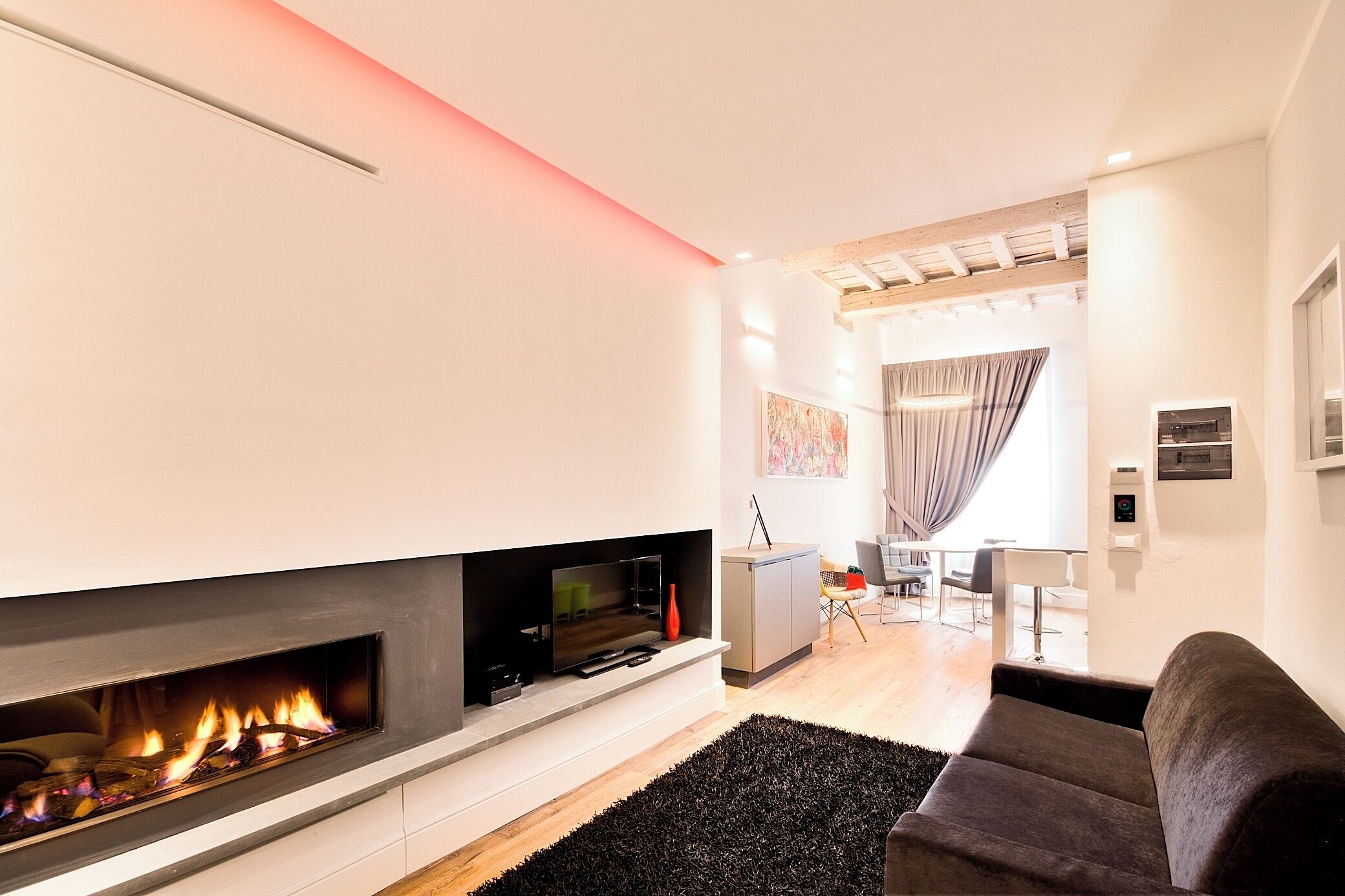 Una sala de estar moderna con chimenea, televisor de pantalla plana, sofá y zona de comedor con mesa y sillas.