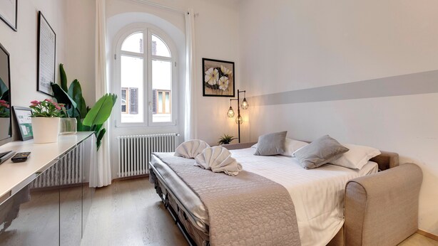 Een slaapkamer met een bed, nachtkastje en een raam met gordijnen.